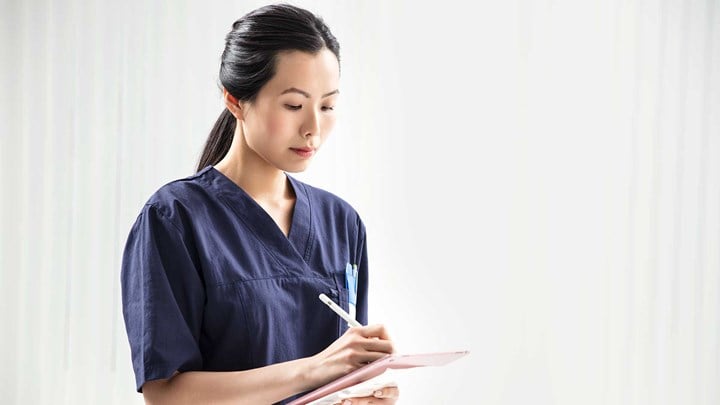 Nurse in blue shirt writing